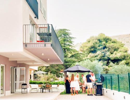a group of people standing outside of a building with an umbrella at Arte Oliva in Grebaštica
