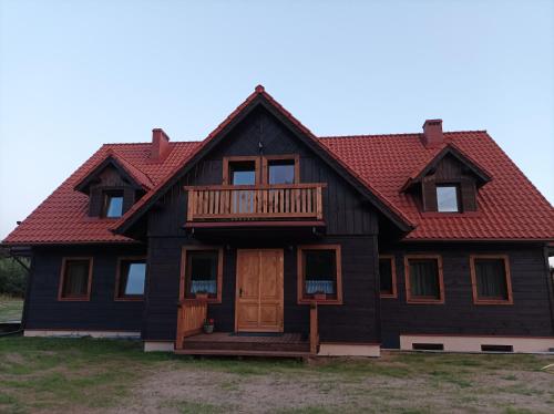 a house with a red roof and a porch at Sosnówka in Krutyń