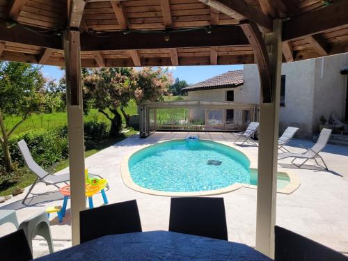 a pool with chairs and a table and a house at Villa au cœur des vignes in Monbazillac