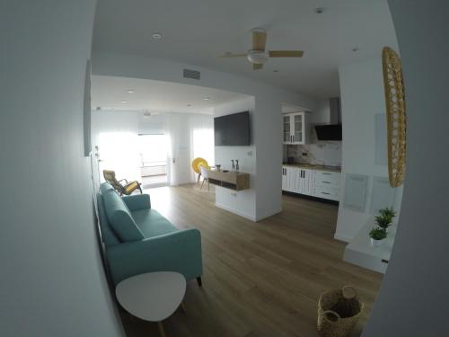 a living room with a blue couch and a kitchen at Seafront Homes in Castillo de BaÃ±os