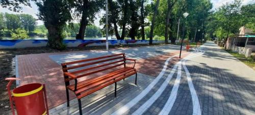 a wooden bench sitting on a sidewalk in a park at Дом-House в Vadul lui Voda in Vadul lui Vodă