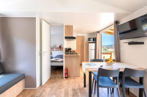 a kitchen and dining room with a table and chairs at Camping maeva Escapades Colomba in Olmeto