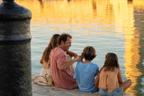 a man and two children sitting next to the water at Iberostar Selection Creta Marine in Panormos Rethymno