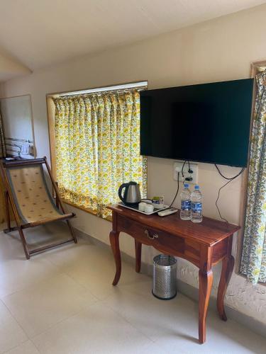 a room with a wooden table with a television on the wall at The Riverstone Agro Farm in Vajapūr