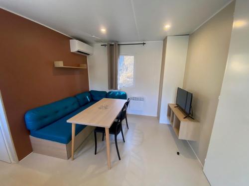 a living room with a blue couch and a table at Camping maeva Escapades Colomba in Olmeto