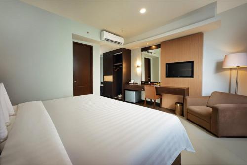 una camera d'albergo con un grande letto bianco e una scrivania di Regantris Malioboro a Yogyakarta