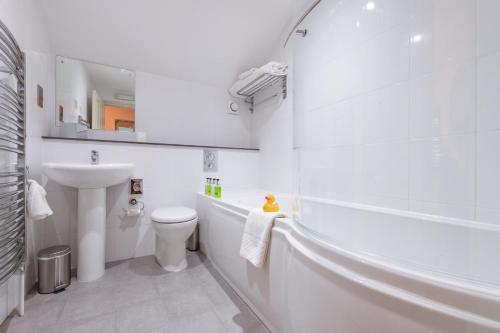 a white bathroom with a toilet and a sink at The King William IV - The Coaching Inn Group in Sedgeford