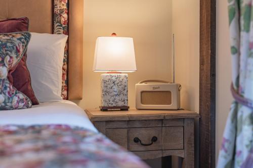 a bed with a lamp and a small tv on a table at The King William IV - The Coaching Inn Group in Sedgeford