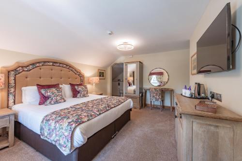 a bedroom with a bed and a desk and a television at The King William IV - The Coaching Inn Group in Sedgeford