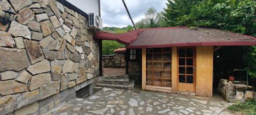 a stone building with a door and a stone wall at Waterfall Guest House in Ribarica