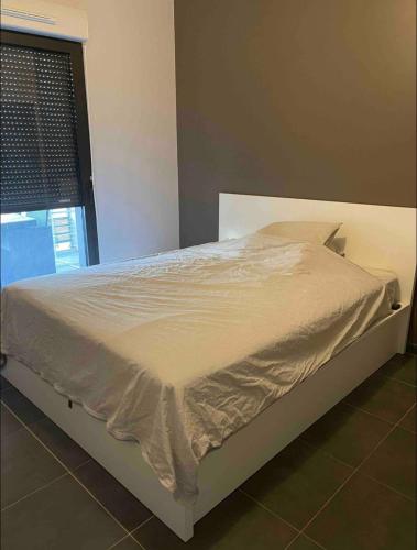 un lit blanc dans une chambre avec une fenêtre dans l'établissement T2 moderne sud Aix en Provence, à Aix-en-Provence