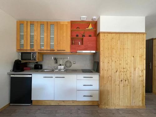 une cuisine avec des armoires en bois et un réfrigérateur blanc et noir dans l'établissement Appartement neuf au coeur du vignoble dans village tous commerces, à Cahuzac-sur-Vère