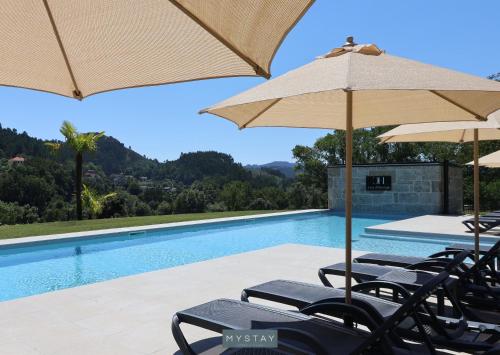 a swimming pool with chairs and umbrellas at MyStay - Casa d'Henrique in Vieira do Minho