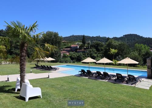 a swimming pool with lounge chairs and umbrellas at MyStay - Casa d'Henrique in Vieira do Minho