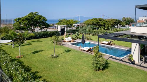 a backyard with a swimming pool and a lawn with chairs at Villa Satori in Kalamata