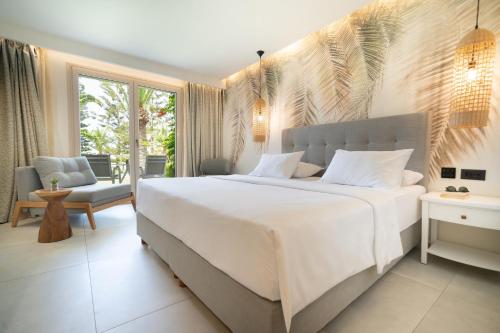 a bedroom with a large white bed and a patio at Iberostar Selection Creta Marine in Panormos Rethymno