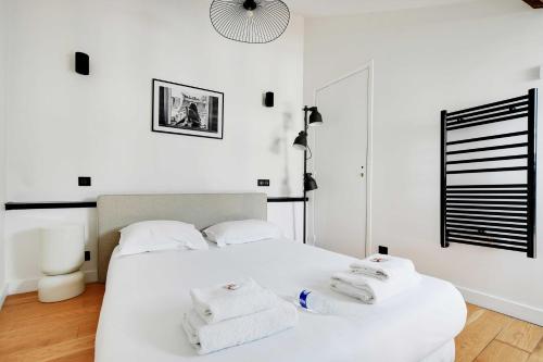 une chambre avec un lit blanc avec des serviettes dessus dans l'établissement Charming apt with ac -Rue des Archives- le marais, à Paris
