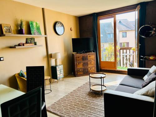 un salon avec un canapé et une télévision dans l'établissement t2 aux portes de Deauville, à Touques
