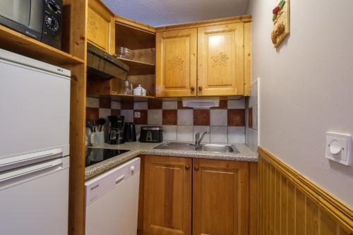 a small kitchen with wooden cabinets and a sink at Résidence Les Balcons De Val Cenis Le Haut in Lanslevillard