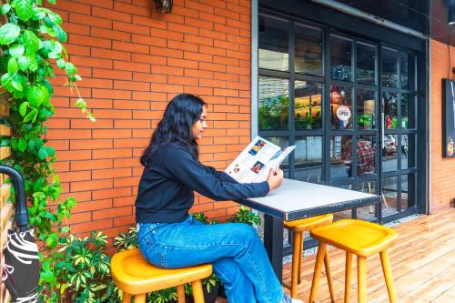 a woman sitting at a table reading a newspaper at Hotel Archana Inn in Cochin
