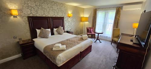 a hotel room with a large bed and a desk at Shendish Manor Hotel & Golf Course in Hemel Hempstead