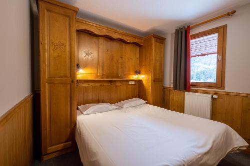 a bedroom with a bed with wooden cabinets and a window at Résidence Les Balcons De Val Cenis Le Haut in Lanslevillard