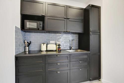 une cuisine avec des armoires grises et un évier dans l'établissement Lovely apartment - 1BR-4P - Buttes-Chaumont, à Paris