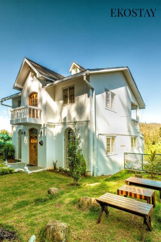 a white house with a bench in front of it at EKOSTAY - Winterfell Chalet Villa in Coonoor