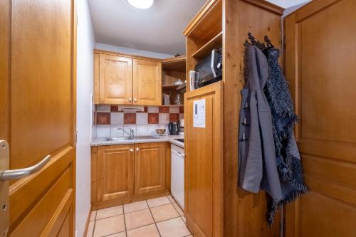 a small kitchen with wooden cabinets and a sink at Résidence Les Balcons De Val Cenis Le Haut in Lanslevillard