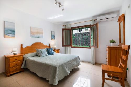 a bedroom with a bed and a chair and a window at Villa Mirafondo in Tías