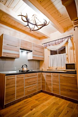 a kitchen with wooden cabinets and a ceiling with a chandelier at Domki Prokop in Ciche