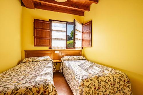 two beds in a room with a window at Comeya in Cangas de Onís