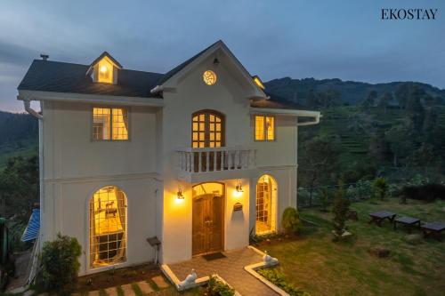 a large white house with its lights on at EKOSTAY - Winterfell Chalet Villa in Coonoor