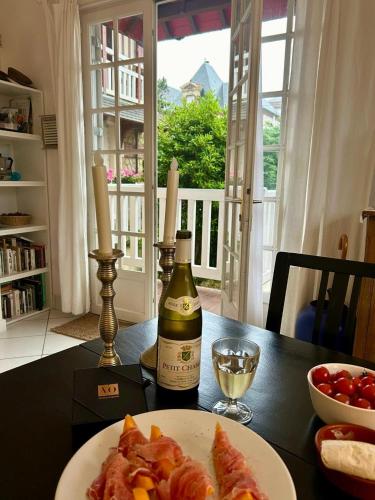 - une table avec une assiette de nourriture et une bouteille de vin dans l'établissement Petit Souplex dans l'hypercentre de Cabourg 80 m de la mer à pied, à Cabourg