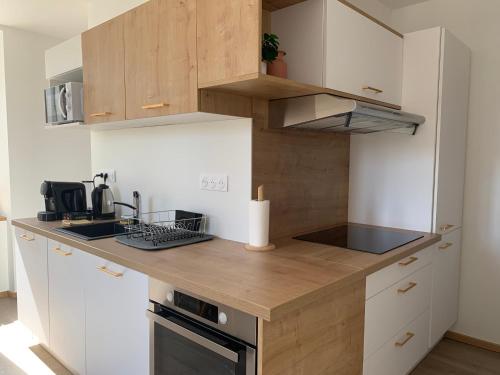 une cuisine avec des armoires blanches et un comptoir en bois dans l'établissement L'Elégant, à Nancy