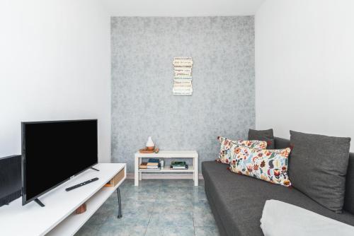 a living room with a couch and a tv at Home2Book Stunning BeachFront Apt, Pozo Izquierdo in Pozo Izquierdo