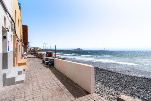 a beach with benches and the ocean at Home2Book Stunning BeachFront Apt, Pozo Izquierdo in Pozo Izquierdo