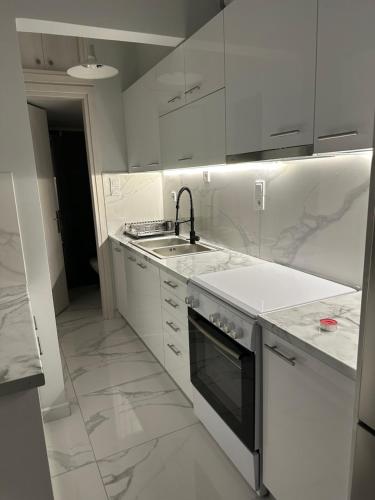 Una cocina blanca con fregadero y estufa. en Ένα διαμάντι στην Ακράτα, en Paralía Akrátas