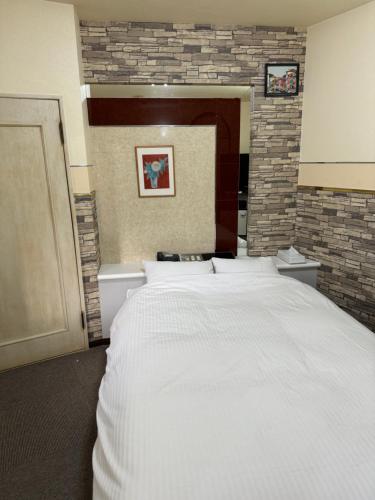 a large white bed in a room with a brick wall at Village lereve in Takeo