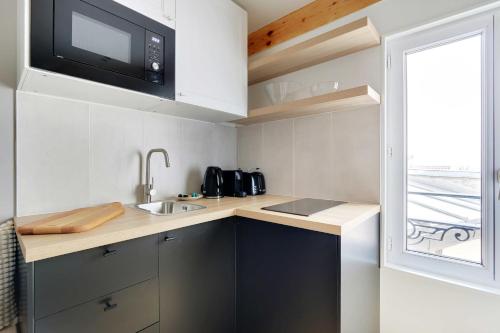 une petite cuisine avec un évier et un micro-ondes dans l'établissement Cosy studio with AC -2P- Sacré-Coeur Montmartre, à Paris