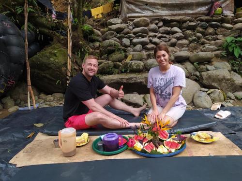 a man and a woman sitting on a blanket with a plate of food at Indra Valley Inn Bukit Lawang in Bukit Lawang