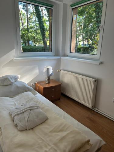 a bedroom with two beds and two windows at Letni domek na wydmie in Pobierowo