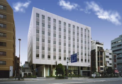 a white building on a city street with buildings at Washington R&BHotel TokyoToyocho in Tokyo