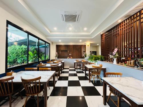 a restaurant with tables and chairs and a checkered floor at USABAI Riverside Boutique Hotel in Chanthaburi