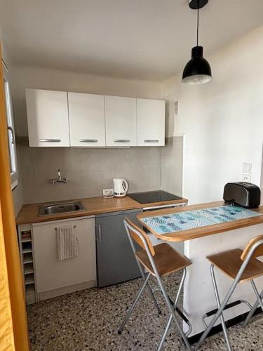 une cuisine avec des armoires blanches et une table et des chaises dans l'établissement Studio climatisé - 3min à pied Gare Saint Charles - 15 min à pieds du Vieux port, à Marseille