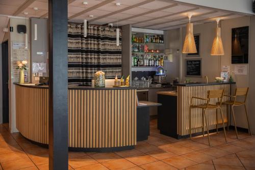 a bar in a restaurant with two bar stools at Kyriad N&icirc;mes Ouest A9 in N&icirc;mes