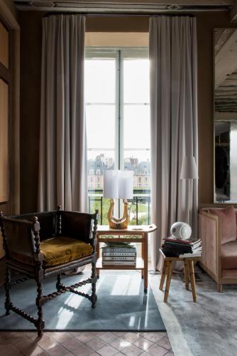 a living room with a couch and a large window at Cour des Vosges - Evok Collection in Paris