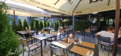 a man sitting at a restaurant with tables and umbrellas at Lakeside Hotel Plitvice in Plitvička Jezera