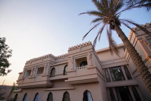a building with a palm tree in front of it at Vijayshree Resort, Hampi in Hampi