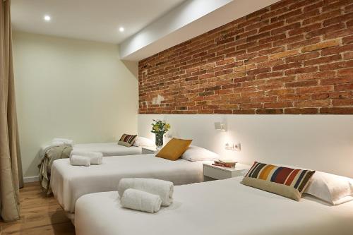 three beds in a room with a brick wall at BBarcelona Sagrada Familia Flats in Barcelona